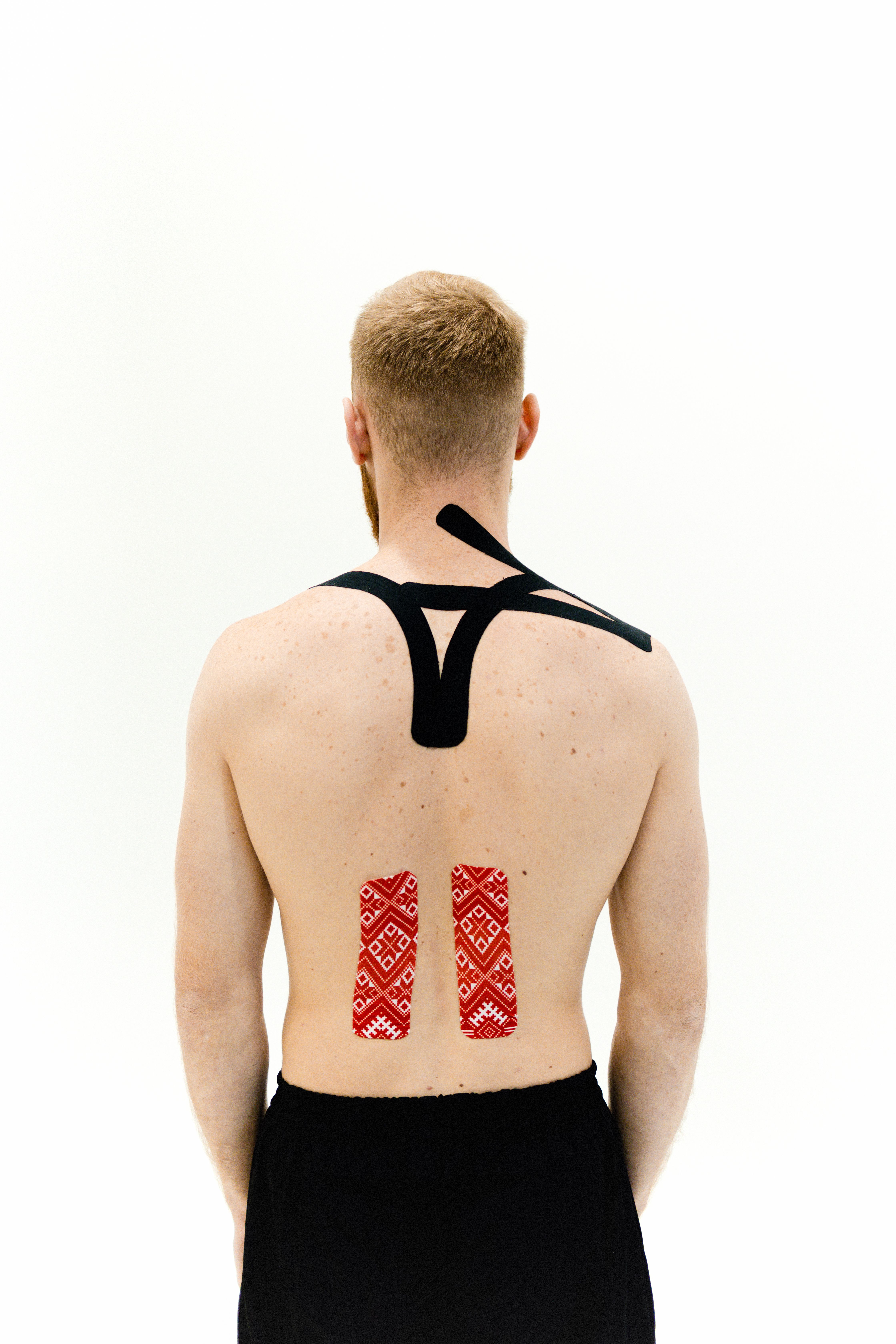 Kinesiologie-Tape auf dem oberen Rücken einer Person zur Unterstützung verspannter Muskulatur
